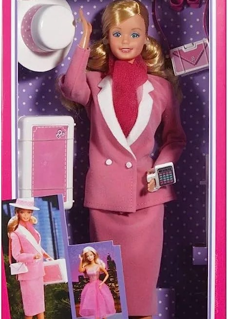 A boxed 'Day-and-Night Barbie' from 1985, dressed in a pink professional dress set and scarf, with a pager, hat, and purse as accessories